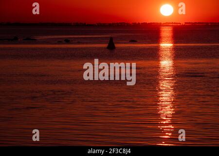 09 March 2021, Mecklenburg-Western Pomerania, Schaprode: The setting sun colours the sky between Rügen and the island of Hiddensee orange-red. Photo: Jens Büttner/dpa-Zentralbild/ZB Stock Photo