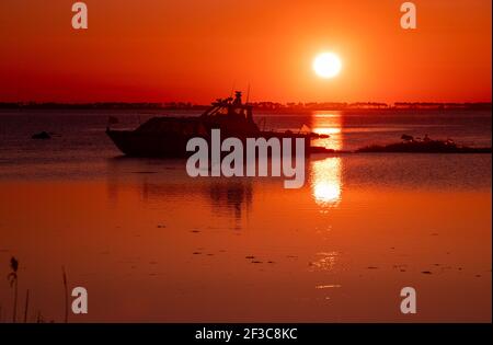 09 March 2021, Mecklenburg-Western Pomerania, Schaprode: A water taxi sails towards Rügen at sunset. The ferry route connects the Baltic Sea islands of Rügen and Hiddensee. Photo: Jens Büttner/dpa-Zentralbild/ZB Stock Photo