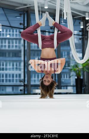 Surface level of young woman practicing aero yoga in sports center Stock Photo