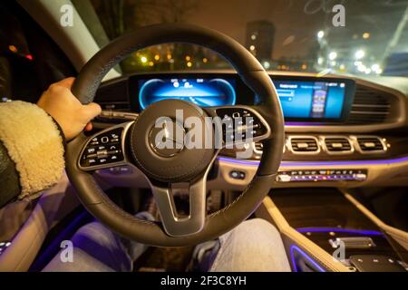 Moscow, Russia - December 24, 2019: The male driver's hand holds the steering wheel of a modern premium SUV Mercedes GLS class. night shooting. driver Stock Photo