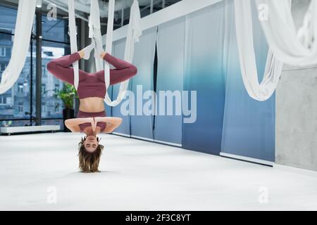 Sportswoman with praying hands practicing fly yoga in sports center Stock Photo