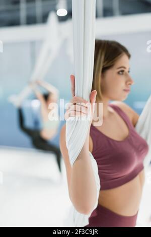 selective focus of young woman warming up with fly yoga strap on blurred background Stock Photo