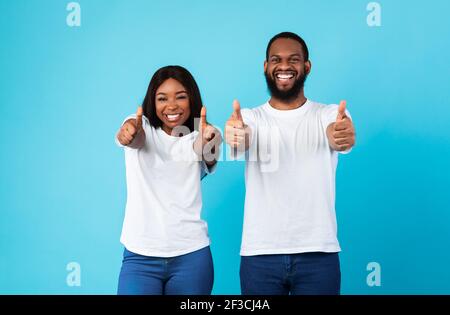 Happy black couple gesturing thumbs up and smiling Stock Photo