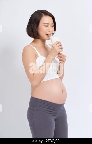 Pregnant woman holding glass of milk in her hand good healty, isolated on white background. Stock Photo