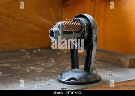 A manual pencil sharpener is tethered to cobwebs an in abandoned school building. Stock Photo