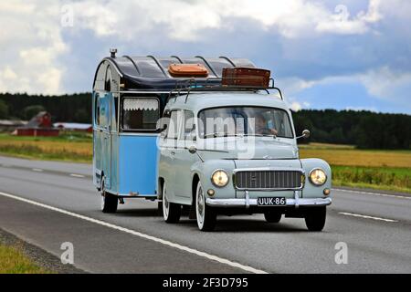 Classic Volvo car PV544, manufactured 1958-65 by Volvo, pulls blue vintage caravan along highway in the summer. Jalasjarvi, Finland. 2016. Stock Photo