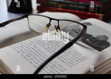 The reader is tired; he has kept his spectacles on the book. Stock Photo