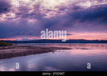 Purple sunset over Vejle Fjord in Denmark. Calm surface waters, surrounded by low forested hills. Beautiful landscape of the Jutland Peninsula. Stock Photo