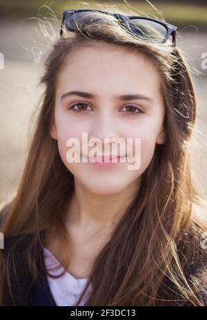 Portrait of a young teen brunette girl with eyeglasses in her hair Stock Photo