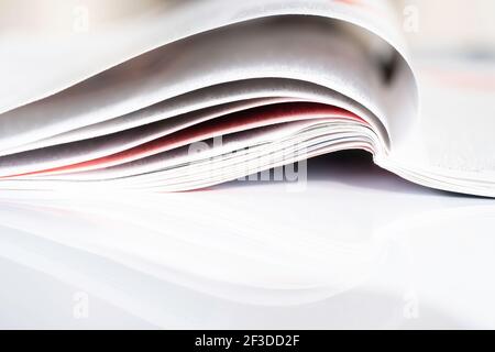 Unfolded magazine reflected on a white surface or table with shallow depth of fiel Stock Photo