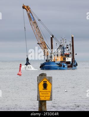 16 March 2021, Mecklenburg-Western Pomerania, Prerow: The dredger 'Elisabeth Høj' is in operation at the access to the emergency harbour Darßer Ort in the core zone of the national park 'Vorpommersche Boddenlandschaft'. The sign on the left says 'Nationalpark Kernzone Betreten verboten'. Twice a year the access road has to be dredged so that the rescue cruiser of the German Maritime Search and Rescue Service (DGzRS) stationed there, the fishing boats and boats in distress can reach the harbour. A new island harbour off Prerow is to replace the current harbour of refuge one day. Photo: Bernd Wü Stock Photo