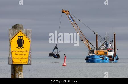 16 March 2021, Mecklenburg-Western Pomerania, Prerow: The dredger 'Elisabeth Høj' is in operation at the access to the emergency harbour Darßer Ort in the core zone of the national park 'Vorpommersche Boddenlandschaft'. The sign on the left says 'Nationalpark Kernzone Betreten verboten'. Twice a year the access road has to be dredged so that the rescue cruiser of the German Maritime Search and Rescue Service (DGzRS) stationed there, the fishing boats and boats in distress can reach the harbour. A new island harbour off Prerow is to replace the current harbour of refuge one day. Photo: Bernd Wü Stock Photo