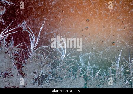 Jack Frost etchings on the window, with a colourful background. Stock Photo