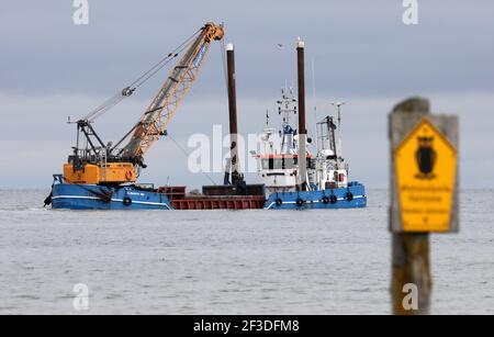 16 March 2021, Mecklenburg-Western Pomerania, Prerow: The dredger 'Elisabeth Høj' is in operation at the access to the emergency harbour Darßer Ort in the core zone of the national park 'Vorpommersche Boddenlandschaft'. The sign on the right-hand side reads 'Nationalpark Kernzone Betreten verboten'. Twice a year the access road has to be dredged so that the rescue cruiser of the German Maritime Search and Rescue Service (DGzRS) stationed there, the fishing boats and boats in distress can reach the harbour. A new island harbour off Prerow is to replace the current harbour of refuge one day. Pho Stock Photo