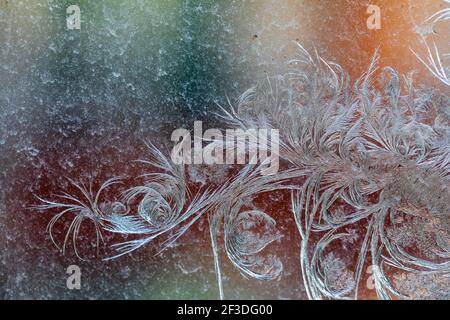 Jack Frost etchings on the window, with a colourful background. Stock Photo