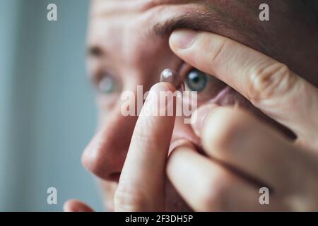 Young man putting contact lens on eye. Themes eyesight and daily routine. Stock Photo