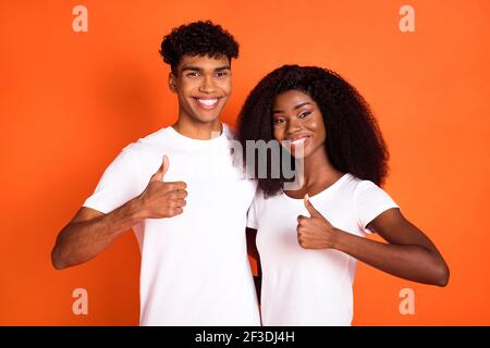 Photo of attractive lady handsome dark skin guy hug show thumbs up isolated on orange color background Stock Photo