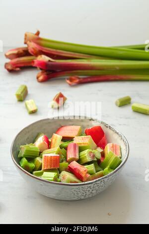 Chopped rhubarb stalks bowl on the kitchen table Stock Photo