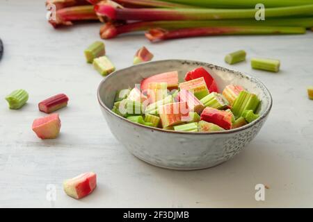 Chopped rhubarb stalks bowl on the kitchen table Stock Photo