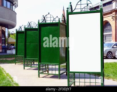 image collage of blank white and space and green metal advertising columns. urban setting. city street background. mockup background. Morris column Stock Photo