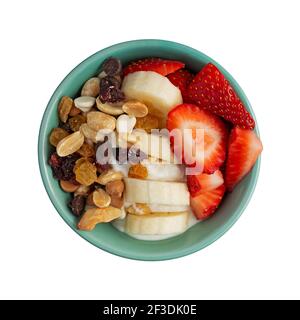 Top view of a bowl with plain Greek yogurt candy trail mix bananas and strawberries on a white background. Stock Photo