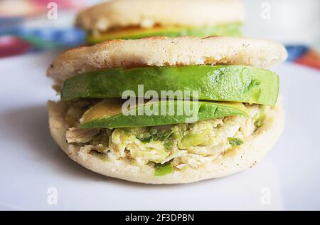 Arepa Reina Pepiada. Venezuelan arepa Reina Pepiada Arepas are is a type of food made of ground maize dough or cooked flour prominent in the cuisine of Colombia and Venezuela. Here Homemade Venezuelan Arepas Close up Background. Arepas Venezolanas Authentic Stock Photo