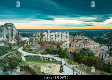 Aerial view of historic village on sea coast. Dramatic orange/teal sky over ocean. Heavy clouds before storm. Stock Photo