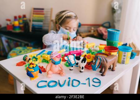 Budva, Montenegro - 17 march 2021: Child girl in a protective mask playing with plasticine. Coronavirus protection concept. Toys in protective Stock Photo