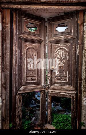 Old traditional wooden door with elaborate relief represantations, in an abandoned house in Archanes village, near Heraklion city, in Crete, Greece Stock Photo