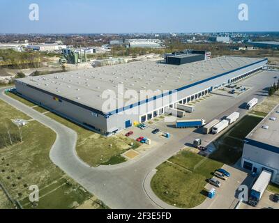 Off-peak hours in logistic distribution center. Drone view of few trucks standing at large warehouse building. Transport and logistics concept. Stock Photo