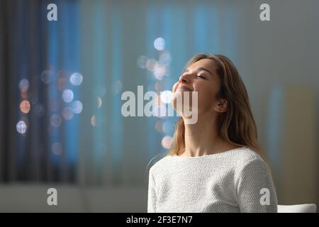 Satisfied tenant breathing fresh air in the night in the living room at home Stock Photo