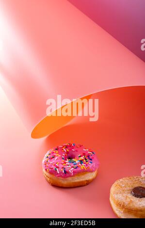 Mix of donuts on pink and caramel swirled background with copy space Stock Photo
