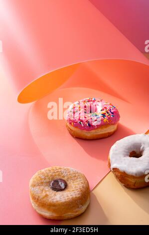 Mix of donuts on pink and caramel swirled background with copy space Stock Photo