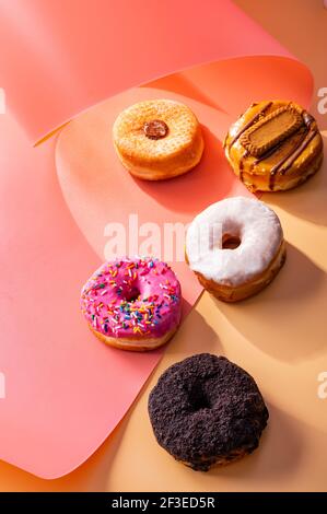 Mix of donuts on pink and caramel swirled background with copy space Stock Photo