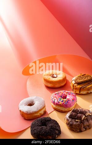 Mix of donuts on pink and caramel swirled background with copy space Stock Photo