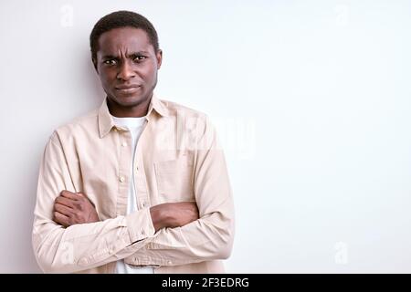 portrait of confident african guy standing with arms folded having serious angry face, wearing light-colored clothing isolated on white studio backgro Stock Photo