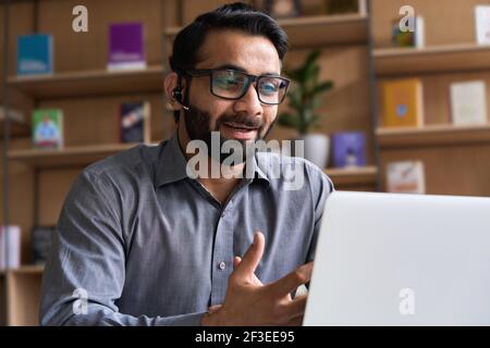 Indian business man speaking having virtual meeting on laptop. Stock Photo