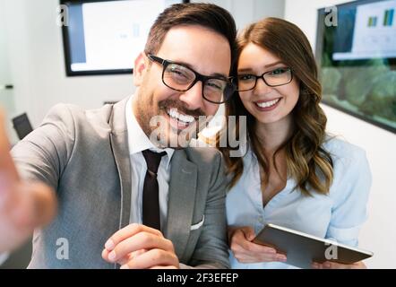 Young happy colleagues having fun while taking selfie in office. Stock Photo