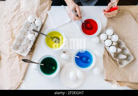 Dyeing Easter eggs with liquid food coloring. Different colors in different bowls. Flat lay. Stock Photo