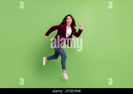 Full size profile photo of optimistic brown hairdo lady jump wear cardigan jeans sneakers isolated on green background Stock Photo