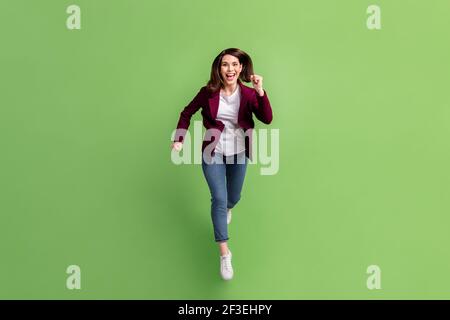 Full size photo of optimistic brown hairdo lady jump wear cardigan jeans sneakers isolated on green background Stock Photo