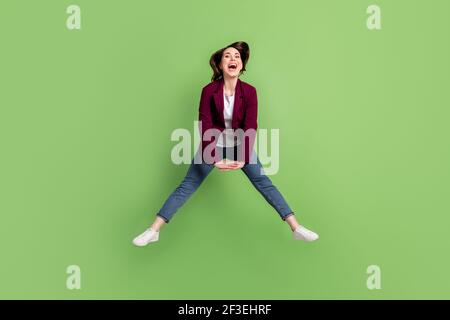 Full size photo of optimistic brown hairdo lady jump wear cardigan jeans sneakers isolated on green background Stock Photo