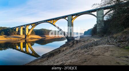 Long concrete road bridge over empty Orlik dam with original Vltava river bed. Beautiful panorama with arched viaduct across water. Podolsko, Czechia. Stock Photo