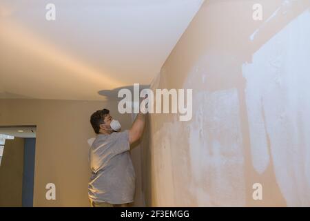 Man sanding the plaster plasterboard in drywall Stock Photo