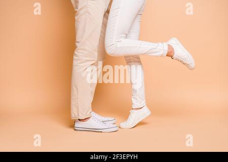 Cropped profile side view of nice couple legs soulmates meet enjoying hugging isolated on beige pastel color background Stock Photo