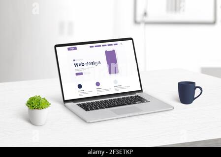 Web design studio concept with laptop computer on clean desk with modern flat design web page on display Stock Photo