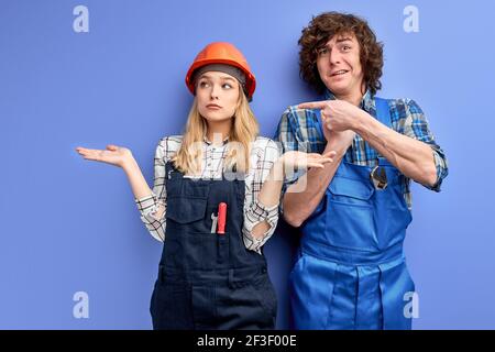 engineers did not fulfill the construction plan correctly, unskilled construction workers dressed in uniform over blue background. woman shrugging whi Stock Photo