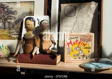 Liverpool Street, London, UK,- 21 September 2020, Spitalfields Antique Market. Two old dolls with broken hands are placed on old book is on counter. W Stock Photo
