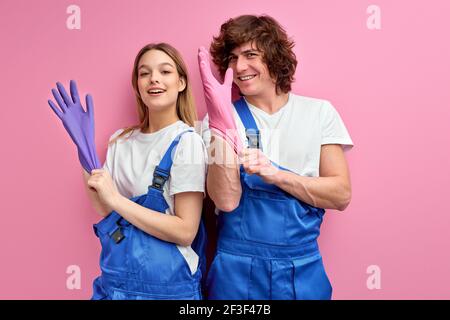 Fun cleaning together. Excited couple in overalls wearing rubber gloves preparing for cleaning, caucasian man and woman doing domestic chores. isolate Stock Photo