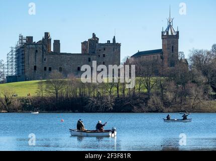 Men fly fishing from boats on Linlithgow Loch with Linlithgow Palace behind. Stock Photo